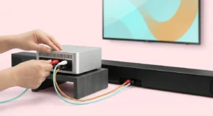 Person connecting RCA cables from a Best Karaoke Machine audio mixer to a black soundbar, illustrating a home karaoke setup.